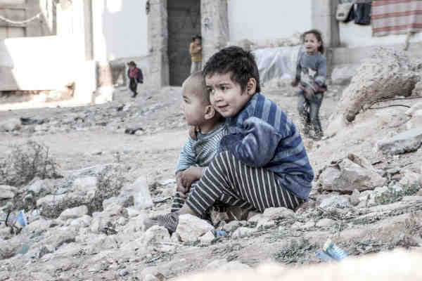In Aleppo, Syria, four-year-old Esraa and her brother Waleed, three, sit on the ground near a shelter for internally displaced persons. Photo: UNICEF / Al-Issa