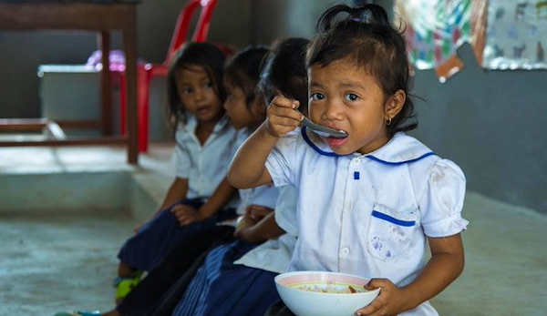 A young girl eats a meal in school before beginning class in Cambodia. Photo: UNICEF/Bona Khoy